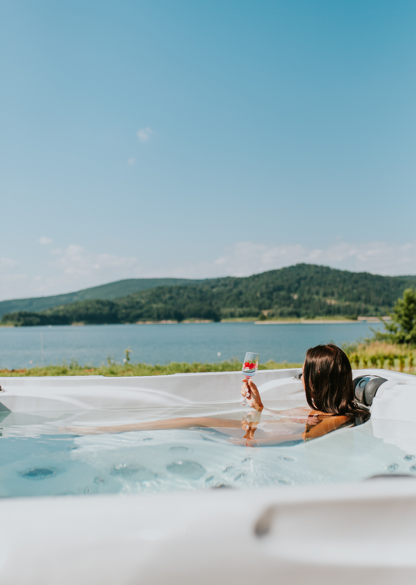 Jacuzzi z widokiem na jezioro — kieliszek wina o zachodzie słońca